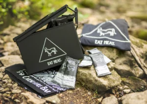 Branded merchandise for The Carnivore Bar displayed outdoors, including a lunchbox, t-shirt, bandana, and packaged bars.